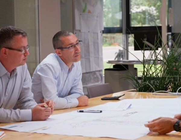 Vue de 5 membres du bureau d'études autour d'un plan